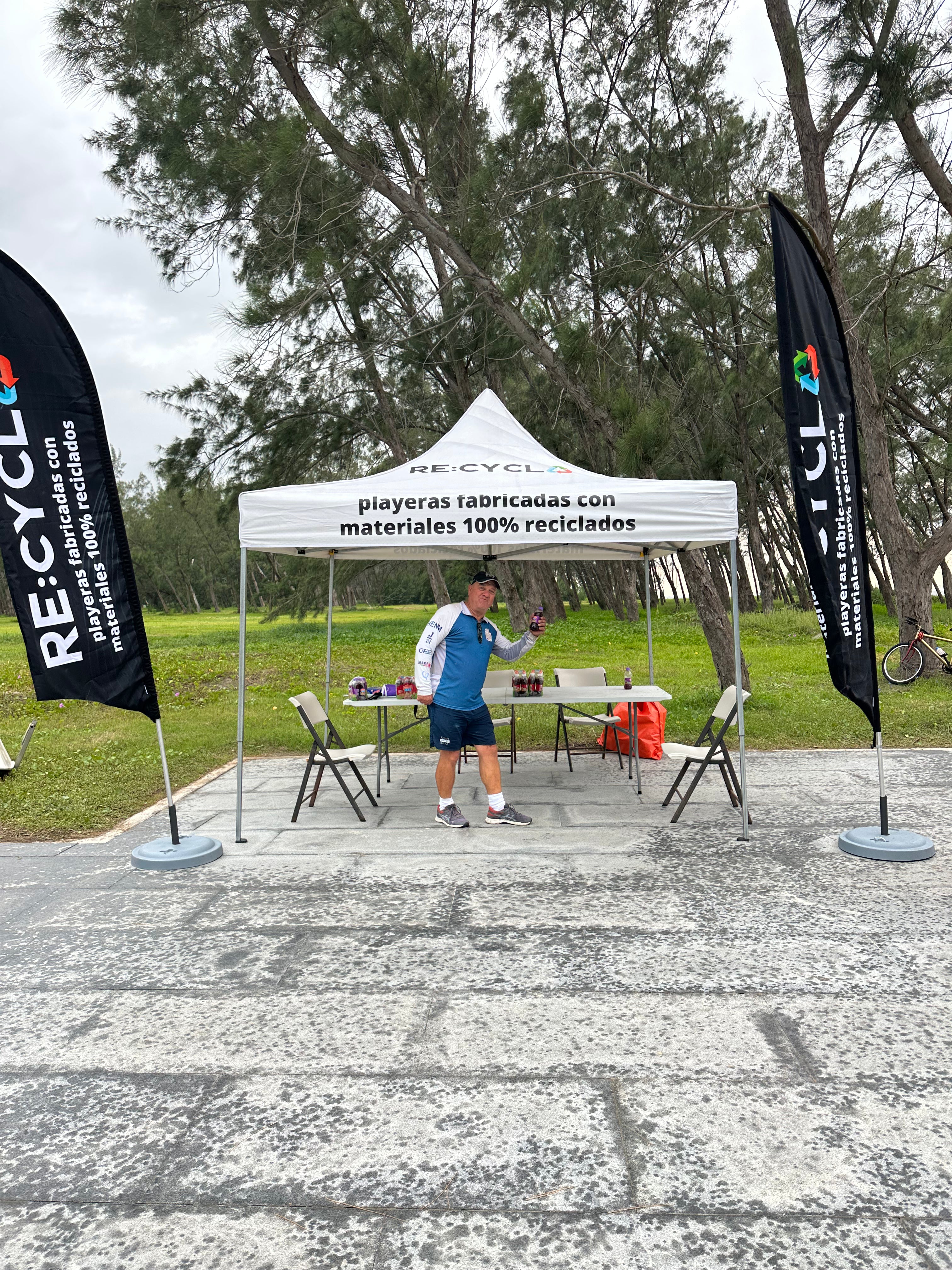 Persona en carpa de Recycla mostrando playeras sublimadas Dry Fit recicladas.